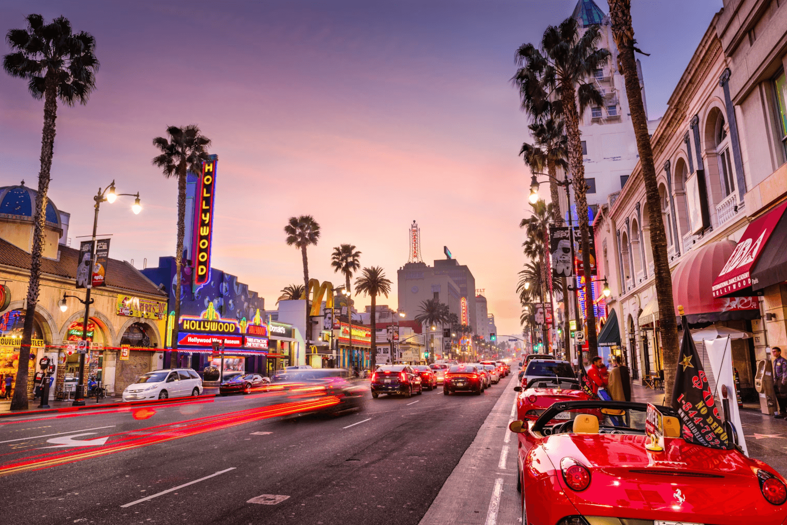 Hollywood Boulevard at sunset with neon lights and palm trees